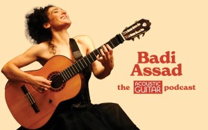 Badi Assad smiling while playing a nylon-string guitar